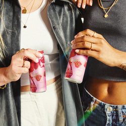 Two people holding floral Daughters of the Vine cans